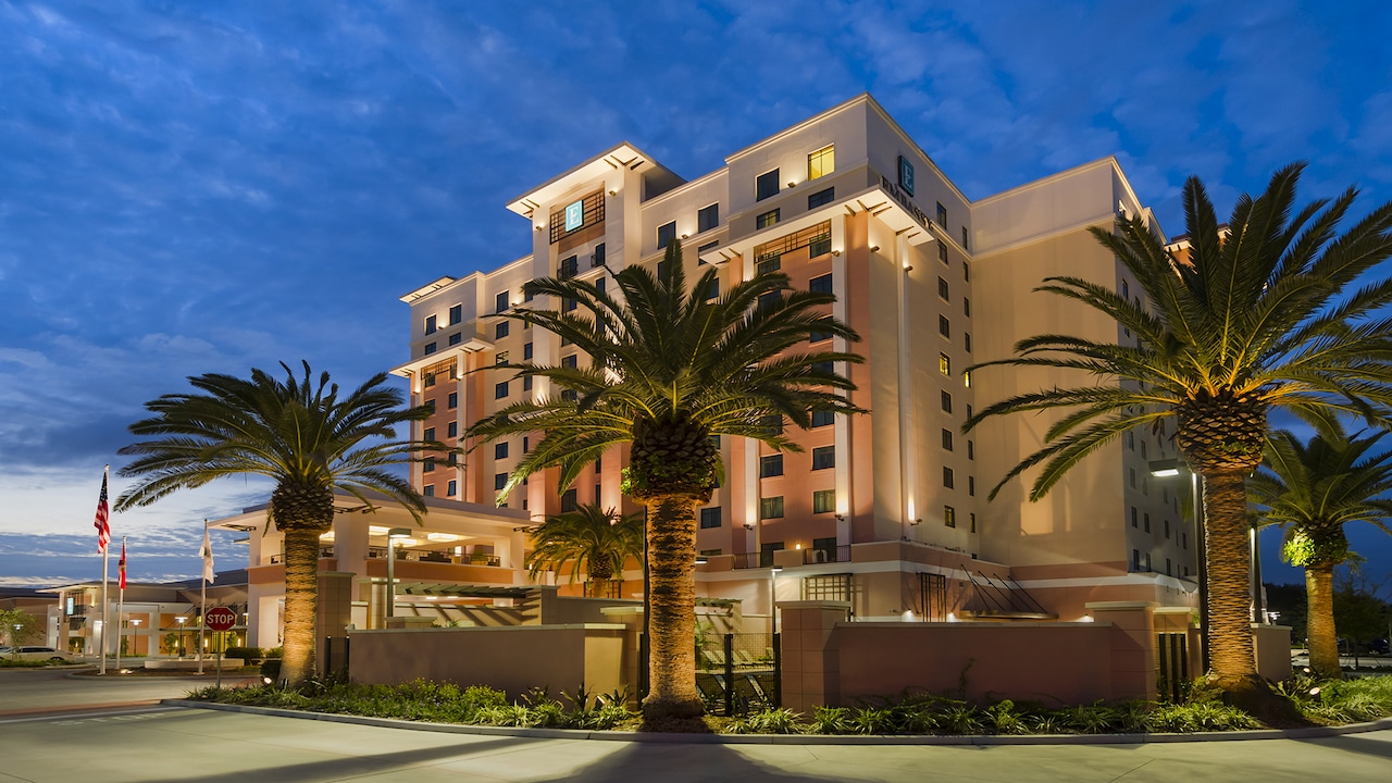 The exterior of Embassy Suites Orlando &mdash; Lake Buena Vista South with palm trees and sophisticated architecture.