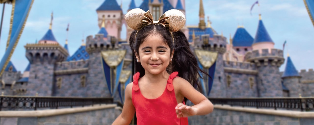 Una niña con sus orejas de Minnie Mouse corre cerca de Sleeping Beauty Castle.
