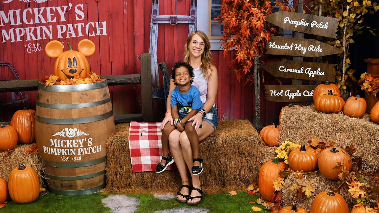 A mother and son posing for a fall themed Mickey’s Pumpkin Patch photo in Disney Springs PhotoPass Studio