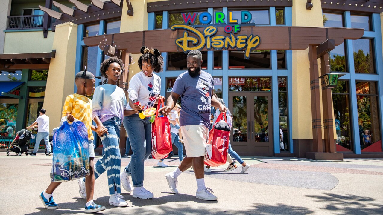 A family walking with shopping bags in front of a World of Disney store at Downtown Disney District