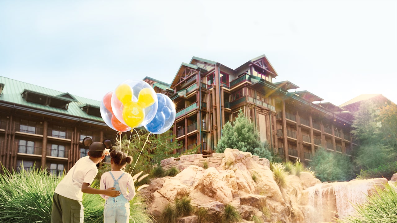 A boy and a girl with balloons standing by the fountain at Disney's Wilderness Lodge