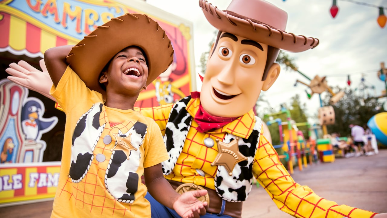 A young Guest dressed as Woody enjoys a laugh with Woody in Toy Story Land at Disney’s Hollywood Studios
