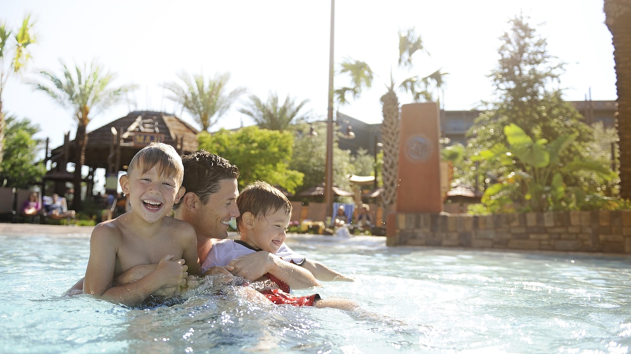 A father and his sons play in the pool