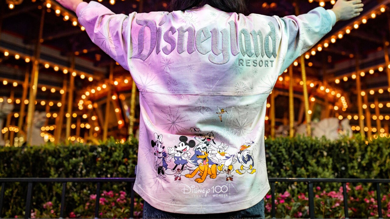 La parte posterior de la camisa de un Visitante, en la que aparecen Mickey, Minnie y otros queridos Personajes de Disney, además de las palabras “Disneyland Resort, Disney 100 Years of Wonder”