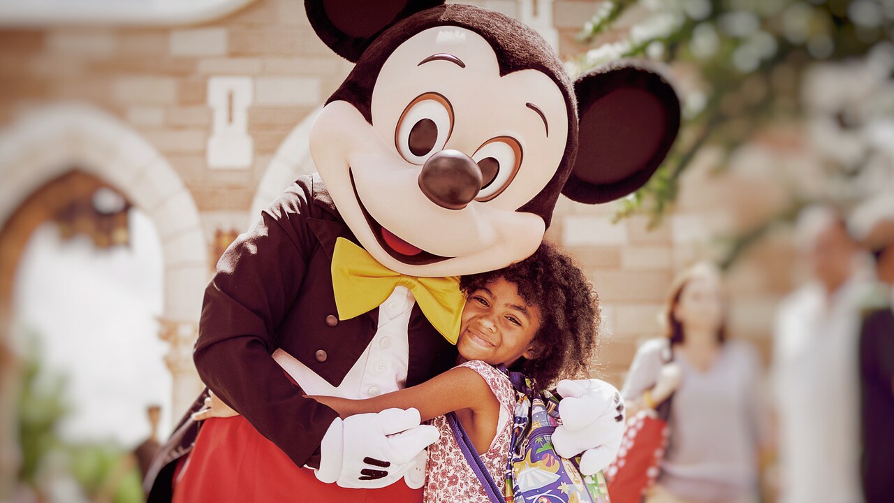 Tipos de Boletos y Beneficios Una niña comparte un abrazo con Mickey Mouse