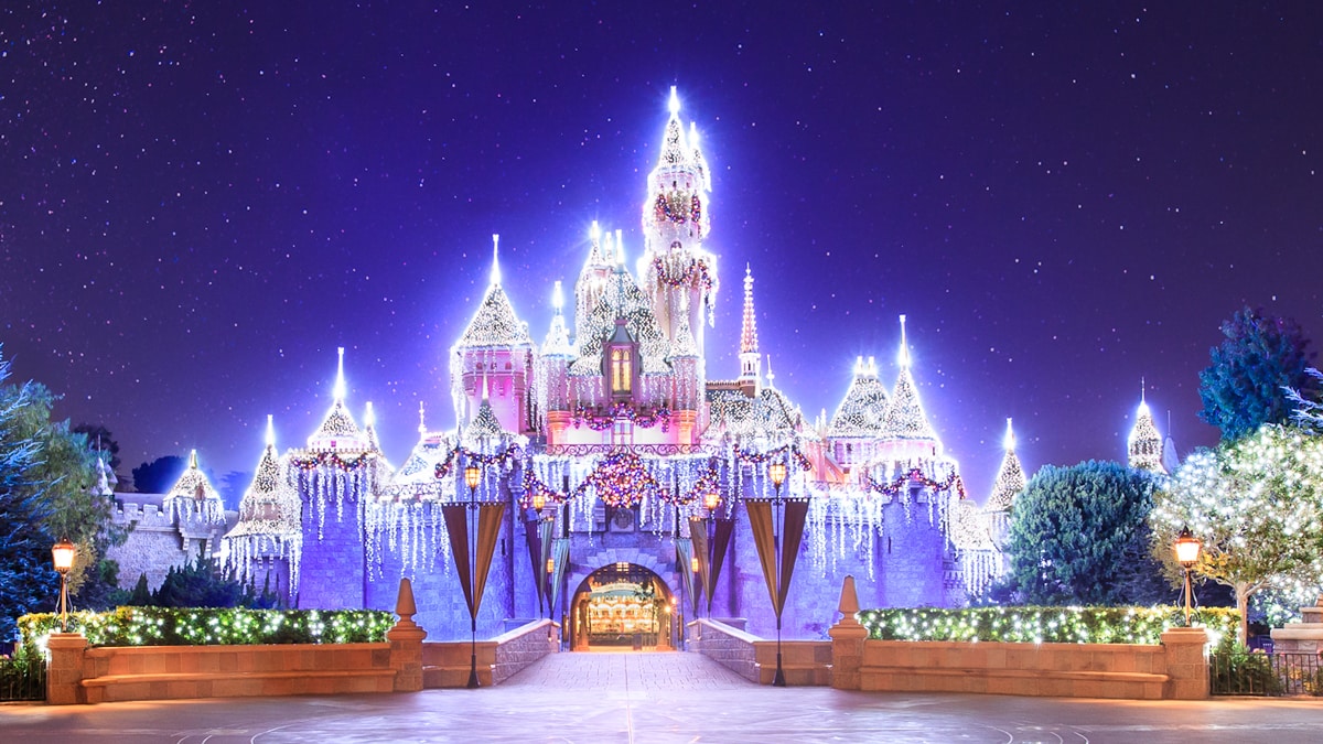 El Castillo de la Bella Durmiente iluminado con luces festivas y decorado con una guirnalda y corona El Castillo de la Bella Durmiente iluminado con luces festivas y decorado con una guirnalda y corona