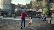 Papá e hija caminan mano en mano hacia la tierra Star Wars: Galaxy’s Edge, en Disneyland Resort