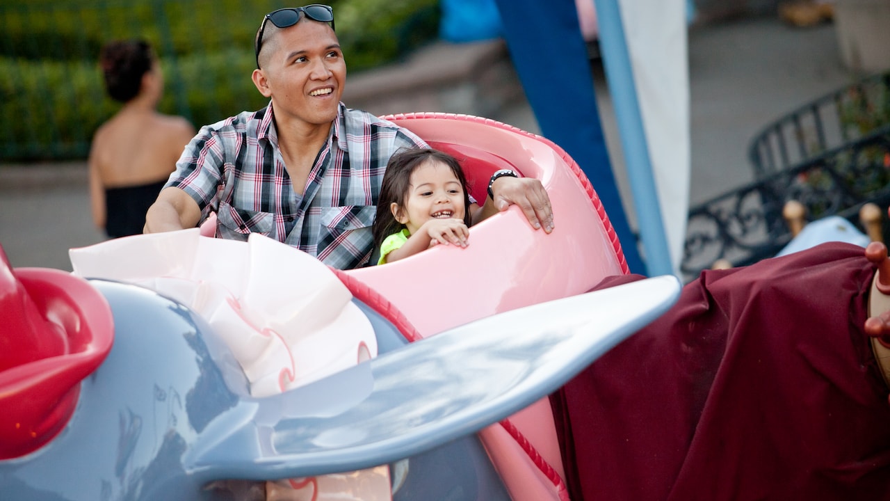 Un hombre y su hija montados en la atracción Dumbo the Flying Elephant