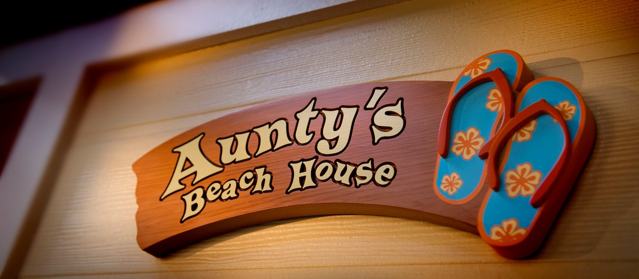 「Aunty's Beach House (アンティーズ・ビーチ・ハウス)」の文字とビーチサンダルを配した木の看板