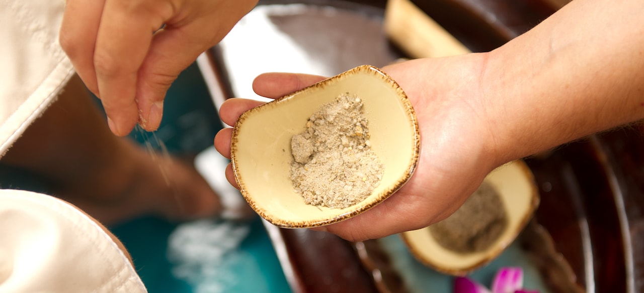 Male hands sprinkling exfoliating salts and aromatics into a small bowl