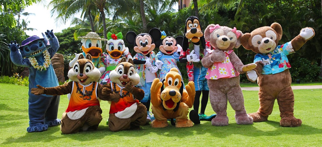 A group shot of 11 Disney Characters, including Mickey, Minnie, Pluto and Stitch, in front of palm trees
