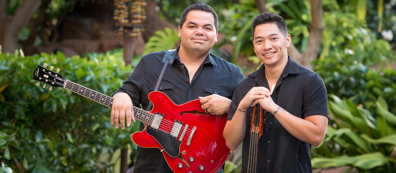 Musicians Halehaku Seabury-Akak, who holds a guitar, stands next to Nicholas Lum, who leans on his bass guitar