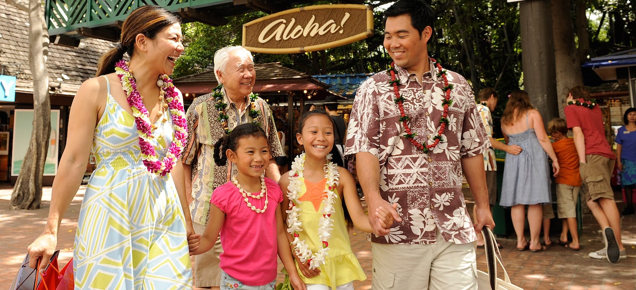 ハワイアンスタイルの服を着て屋外のショッピング・プロムナードを歩く家族