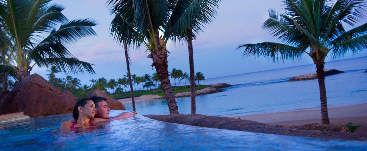 A mature couple leans toward one another in a whirlpool spa while gazing at the ocean