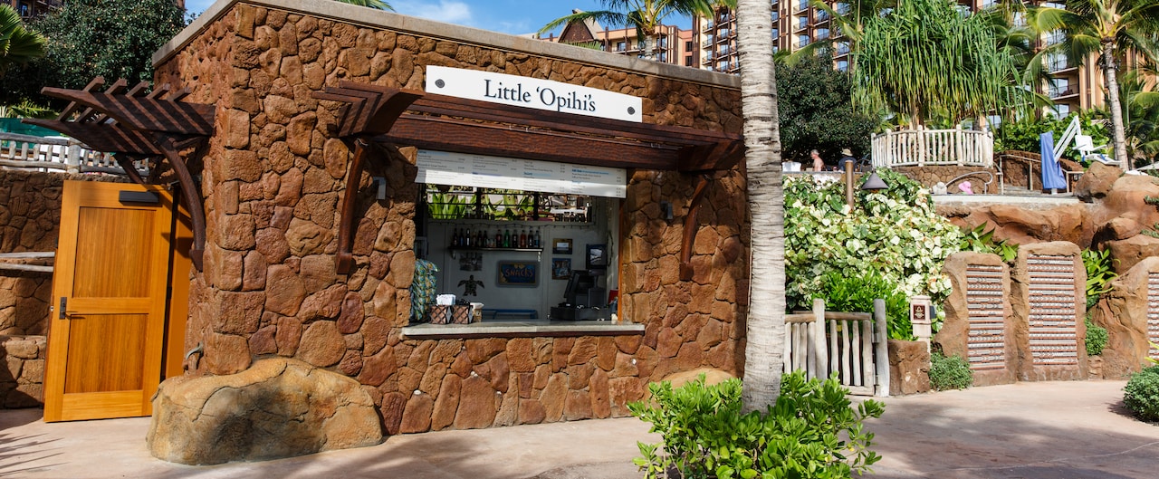 The exterior of Little 'Opihi's, a rectangular, stone shack with a quick service window