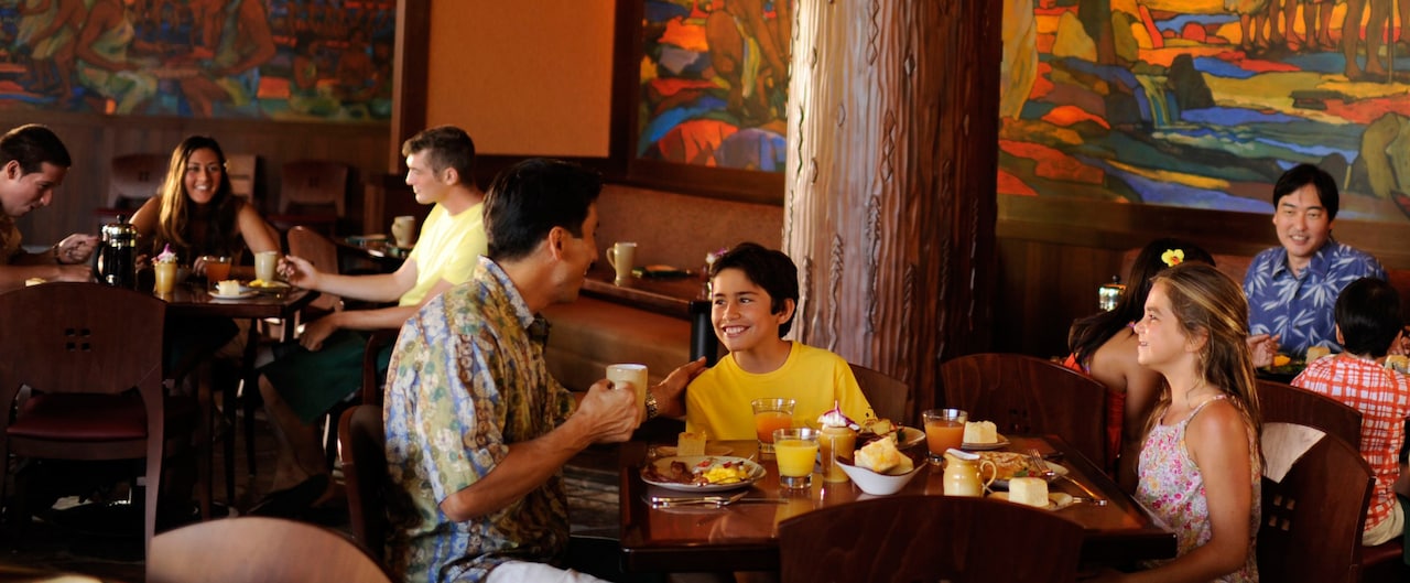 A father and son in an animated conversation at breakfast while a young daughter looks on