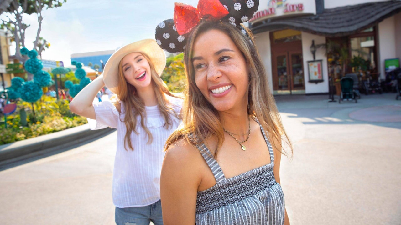 Dos mujeres sonrientes, una con orejas de Minnie, frente a Tortilla Jo’s en Downtown Disney District