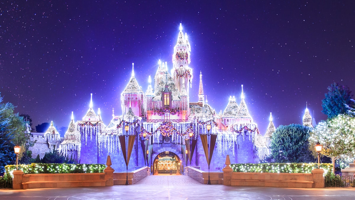 El Castillo de la Bella Durmiente iluminado con luces festivas y decorado con una guirnalda y corona