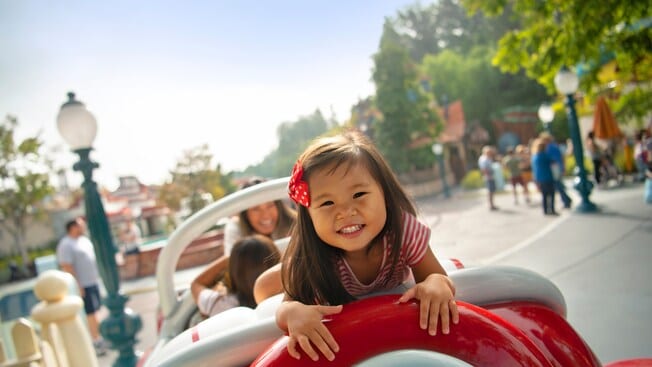 Una niña va mirando hacia atrás en un auto caricaturezco de Mickey’s Toontown