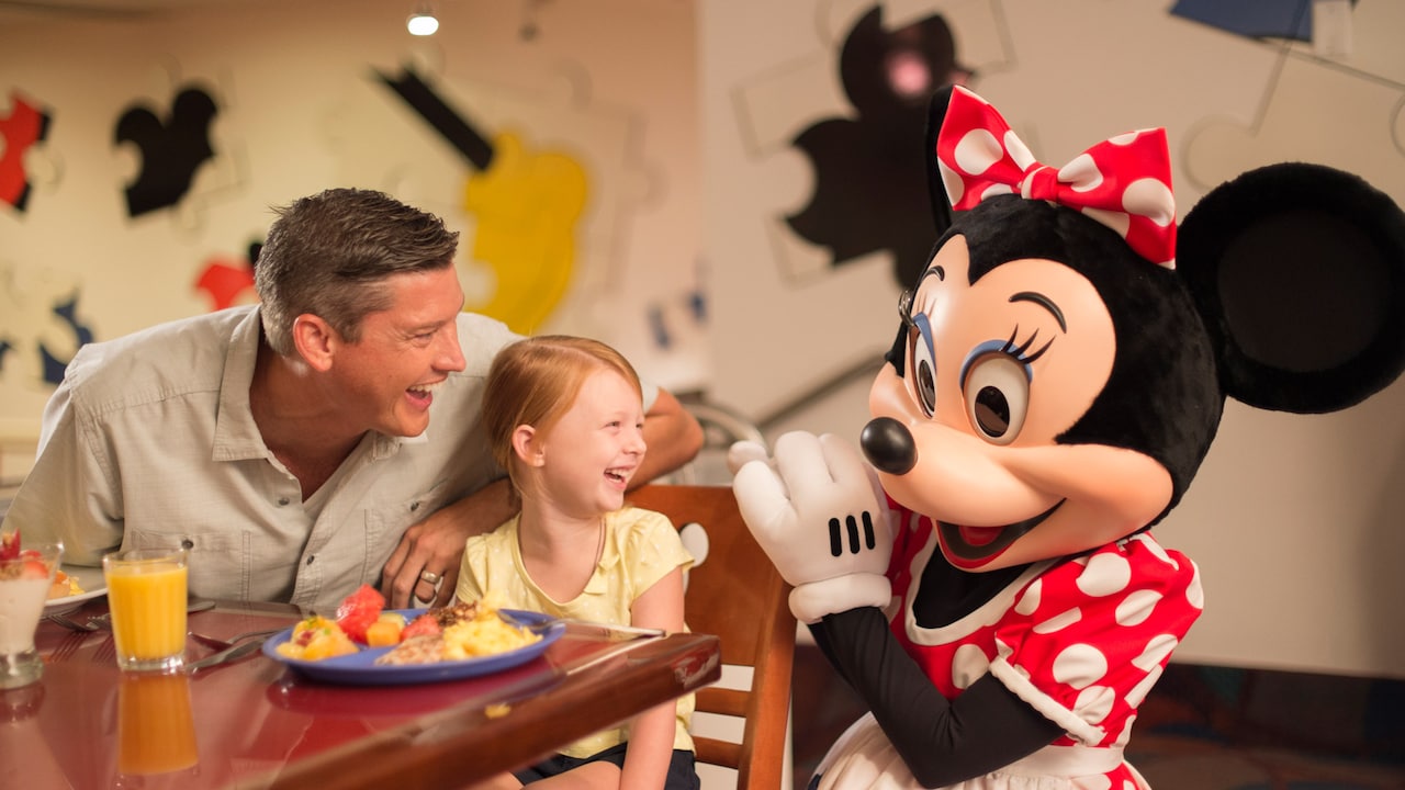 Niño y adulto sonríen, disfrutando a Minnie Mouse en una Comida con los Personajes
