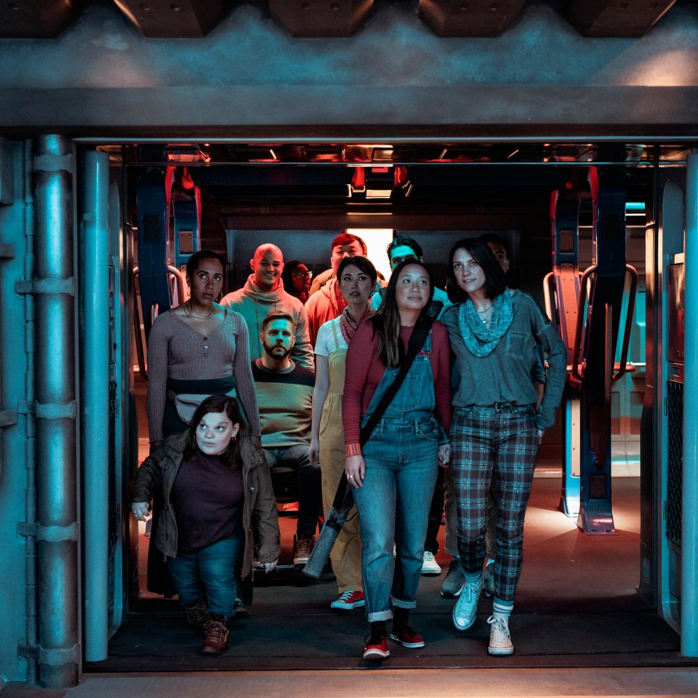 Un grupo de Visitantes, que incluye a un hombre en silla de ruedas y una persona pequeña, entran en la atracción Star Wars: Rise of the Resistance