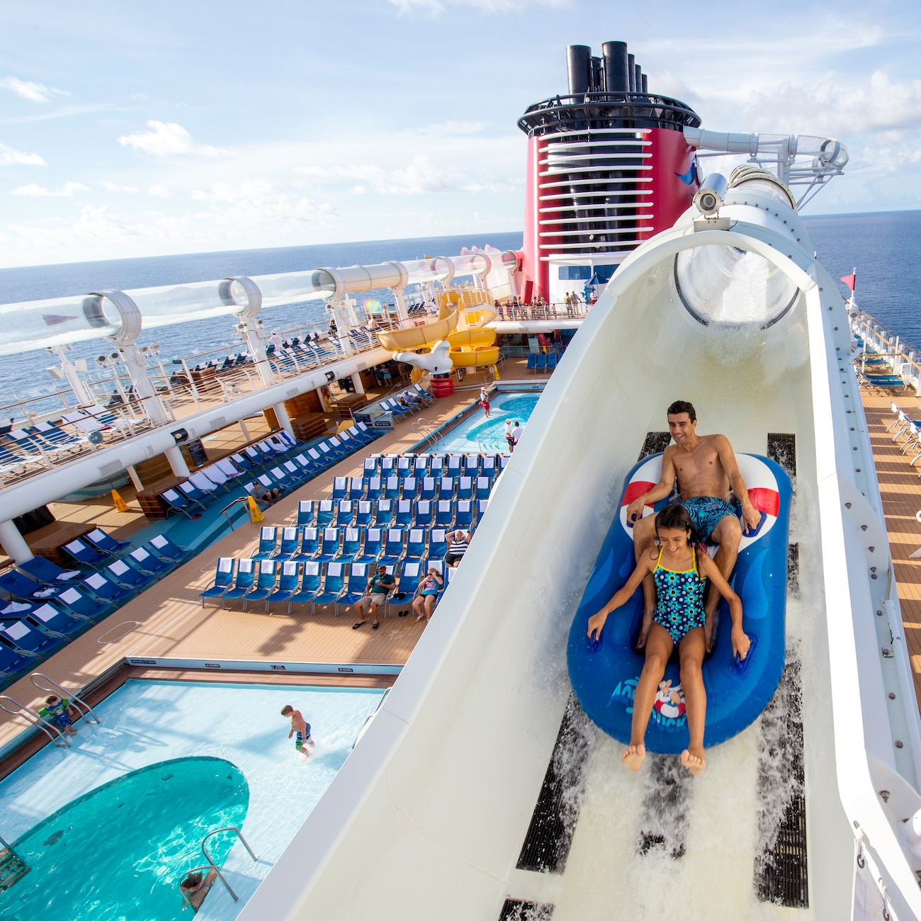 A boy and girl on a raft plunging down a water tube on a Disney cruise ship