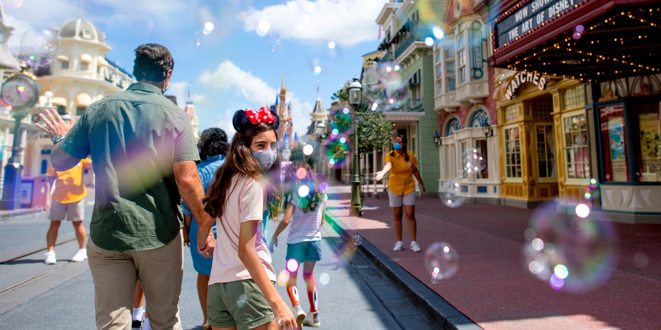 Dad and Daughter walk down main street USA surrounded by bubbles in Magic Kingdom