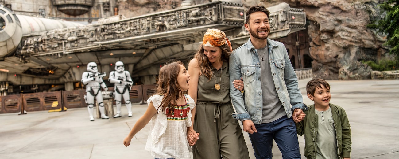 Una familia en Star Wars: Galaxy's Edge, con Stormtroopers de la Primera Orden y el Millennium Falcon de fondo