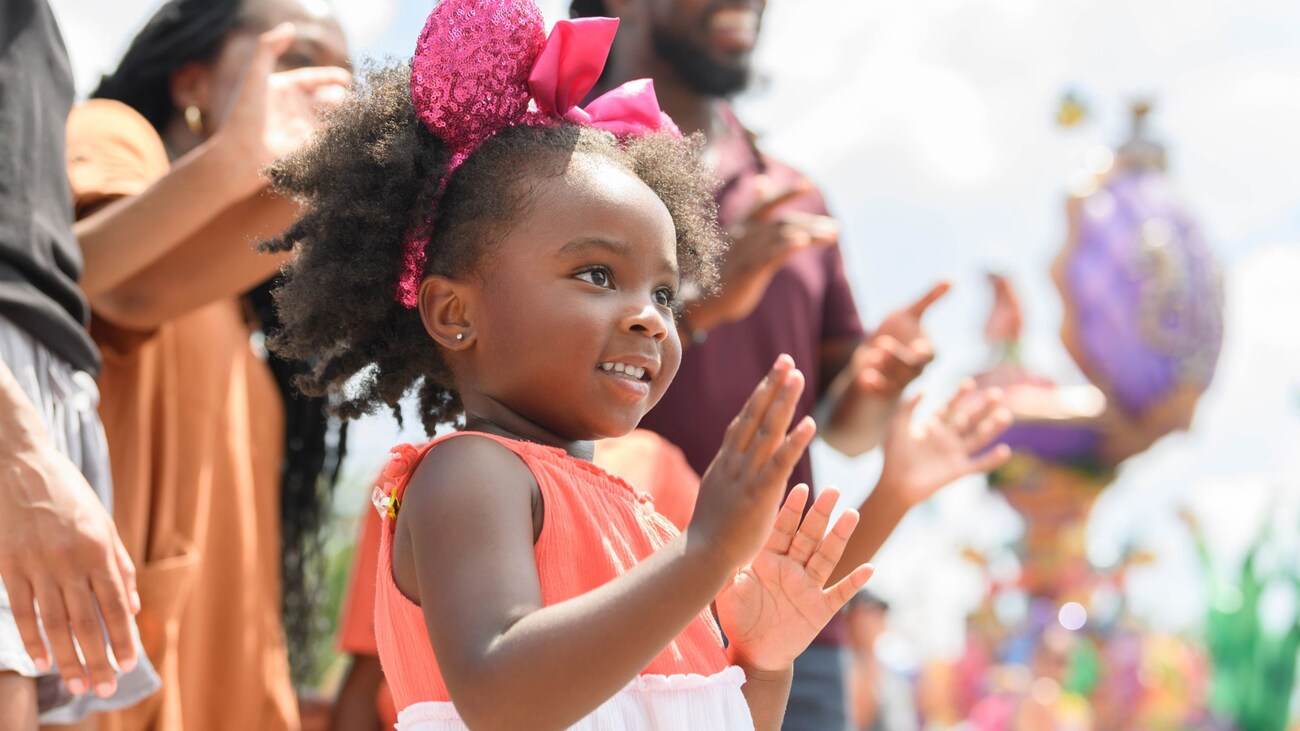 A young Guest happily clapping during the Disney Festival of Fantasy Parade in Magic Kingdom park