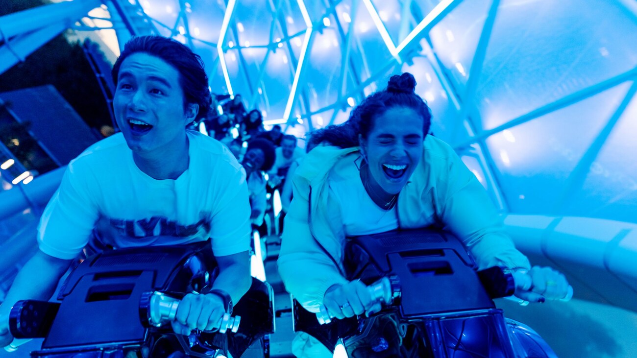 Dos personas sonríen en la atracción Tron Lightcycle Run en Walt Disney World Resort
