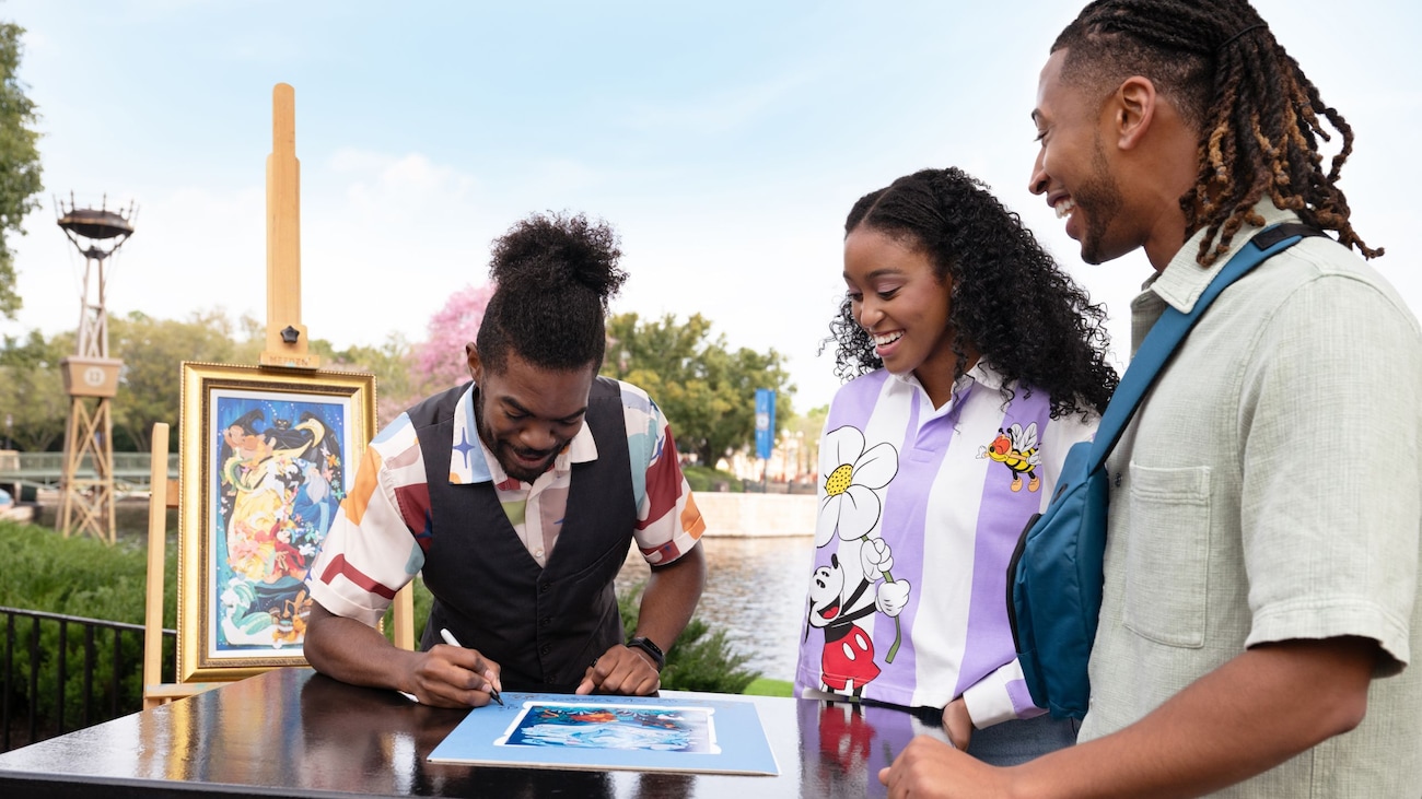 Un artista de retratos de Disney autografiando sus obras para dos Visitantes