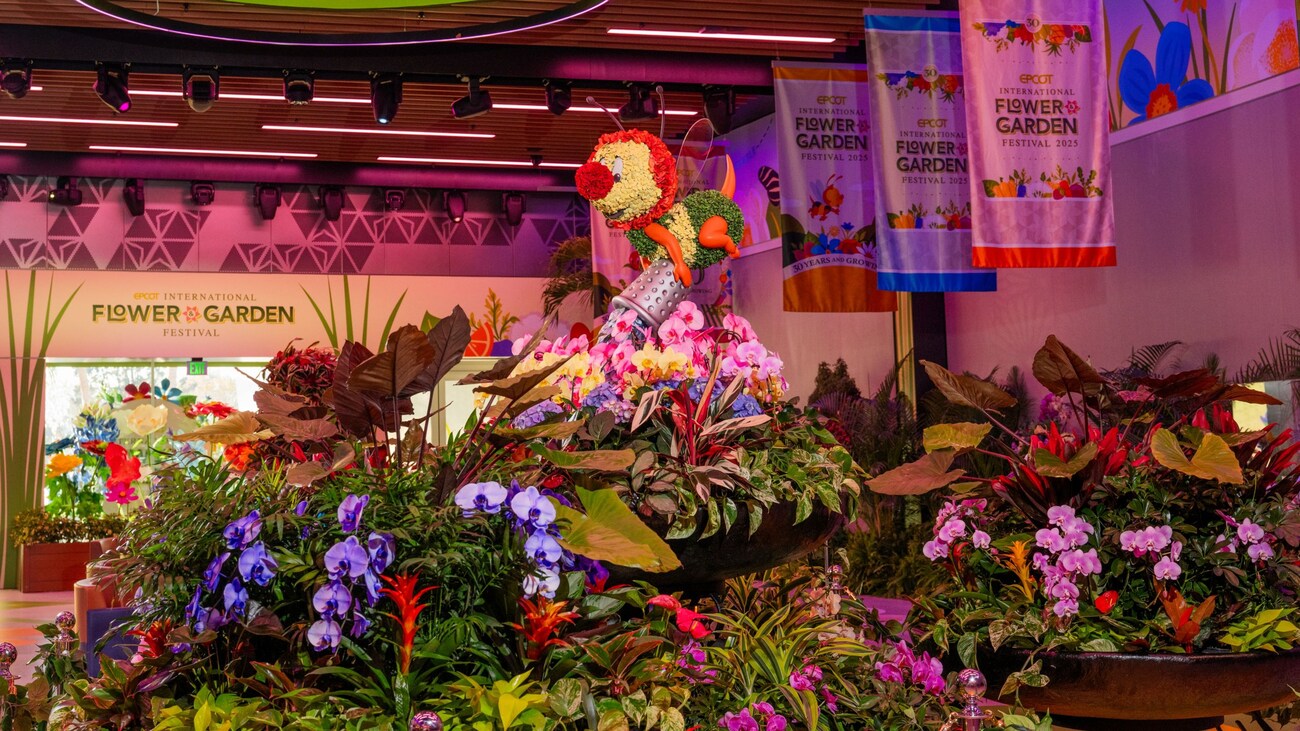 A topiary statue of Spike the Bee pouring a bucket of blossoms into a large planter at the Epcot International Flower & Garden Festival