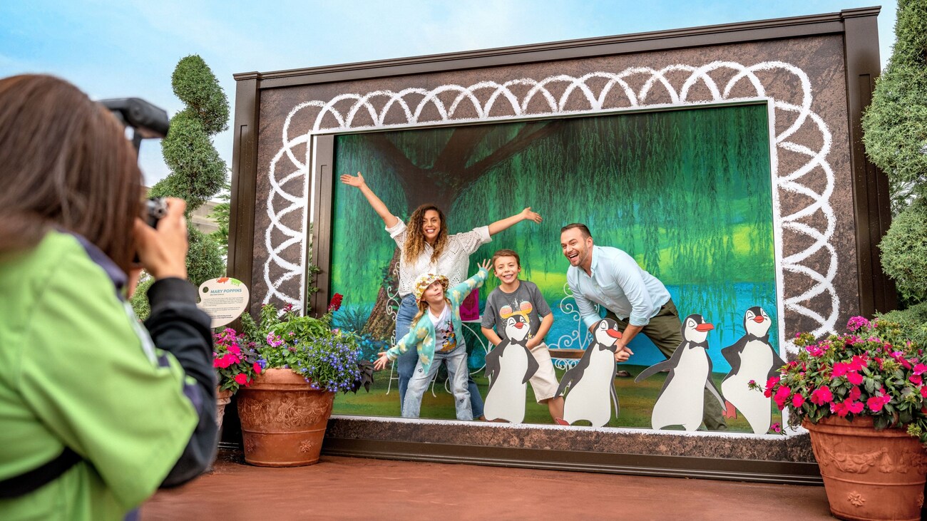 A family posing on stage with 4 animated penguin waiters from Mary Poppins