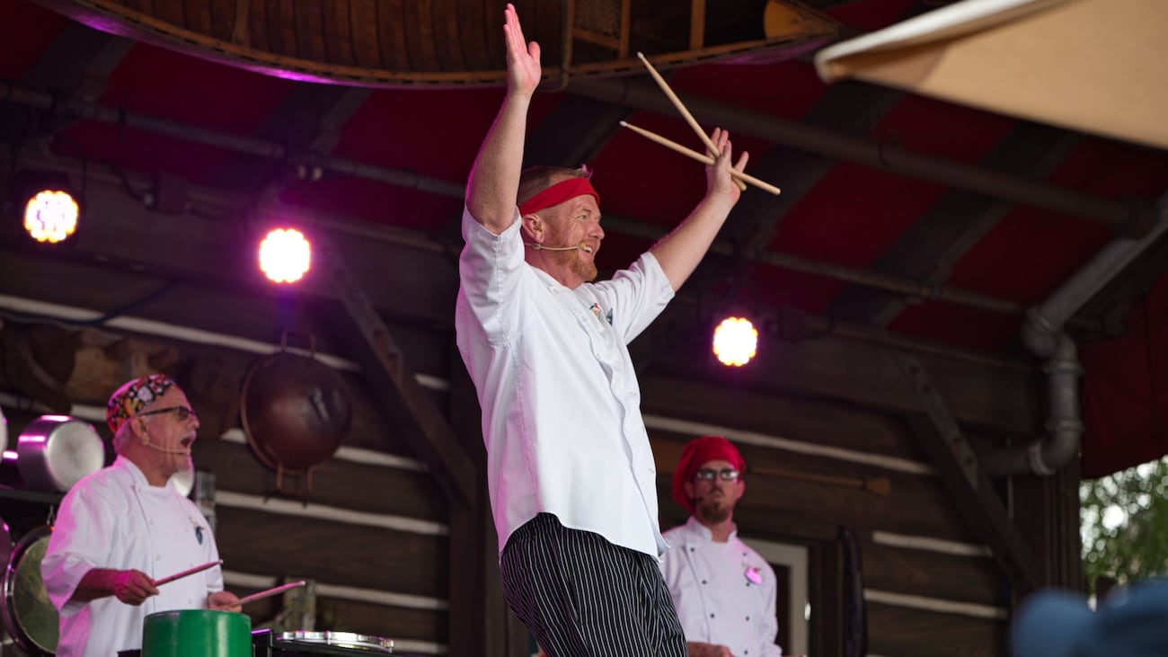 Two performers playing metal cans as percussion instruments  