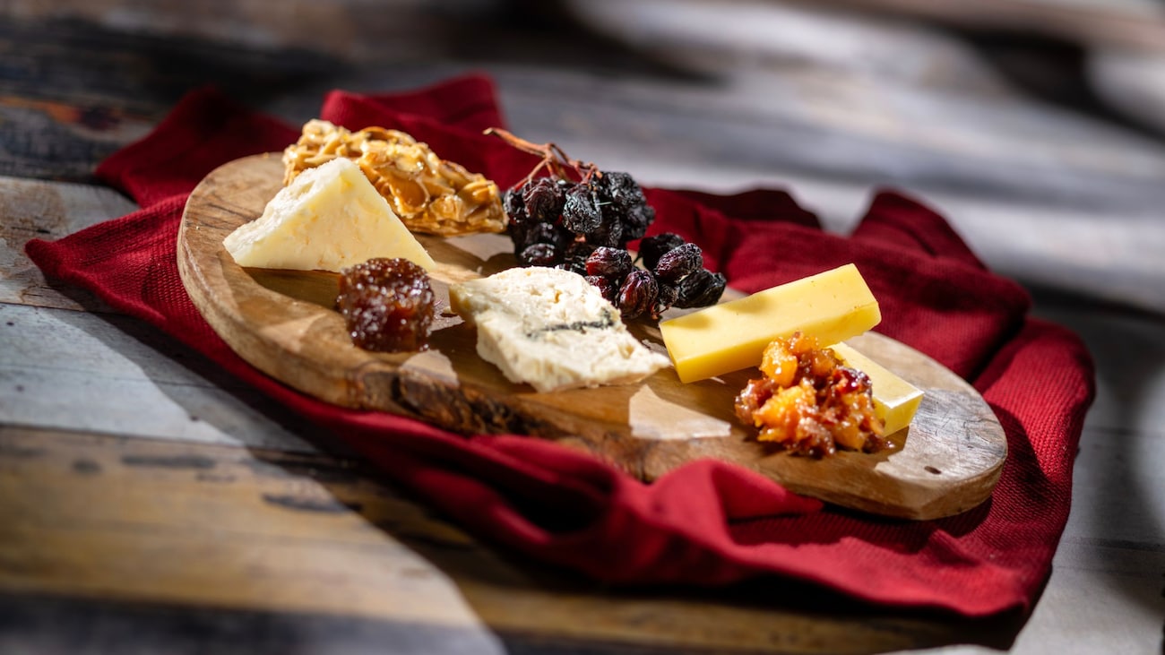 A Selection of Wisconsin Cheeses served on a wooden board with dried fruit