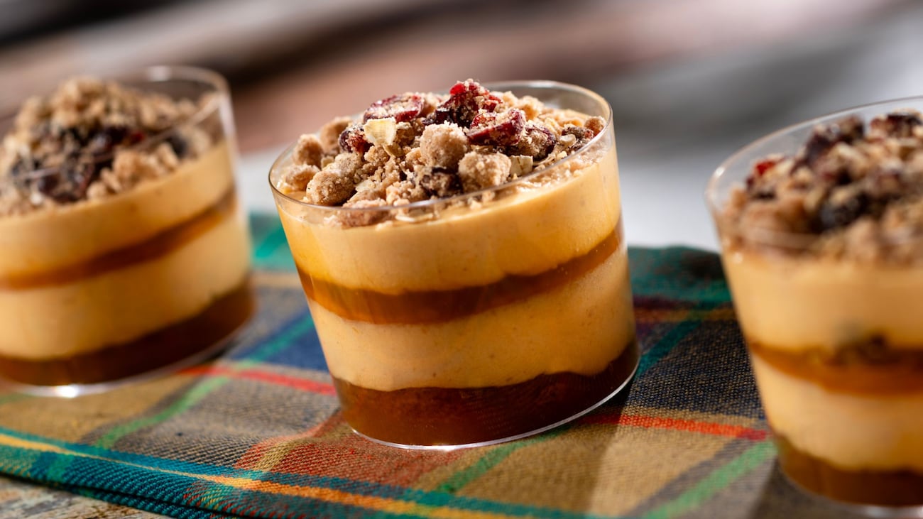 Three individual Pumpkin Cheesecake Mousse Trifles layered with citrus sauce and spice cake, topped with cranberry streusel