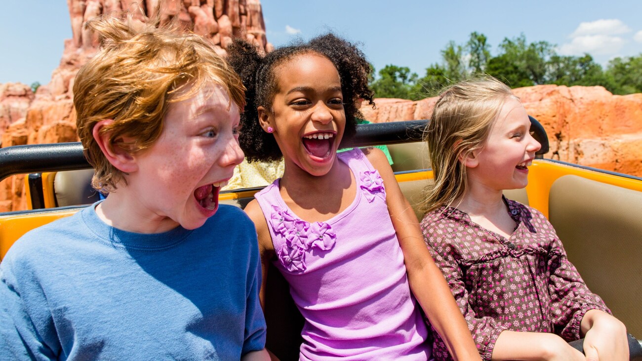 Three smiling children riding Big Thunder Mountain Railroad
