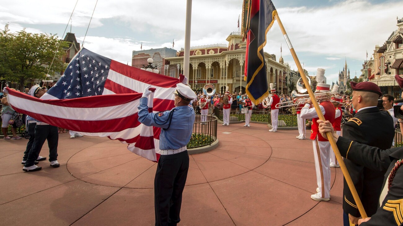US military service members lower the American flag during the daily flag retreat in Magic Kingdom park