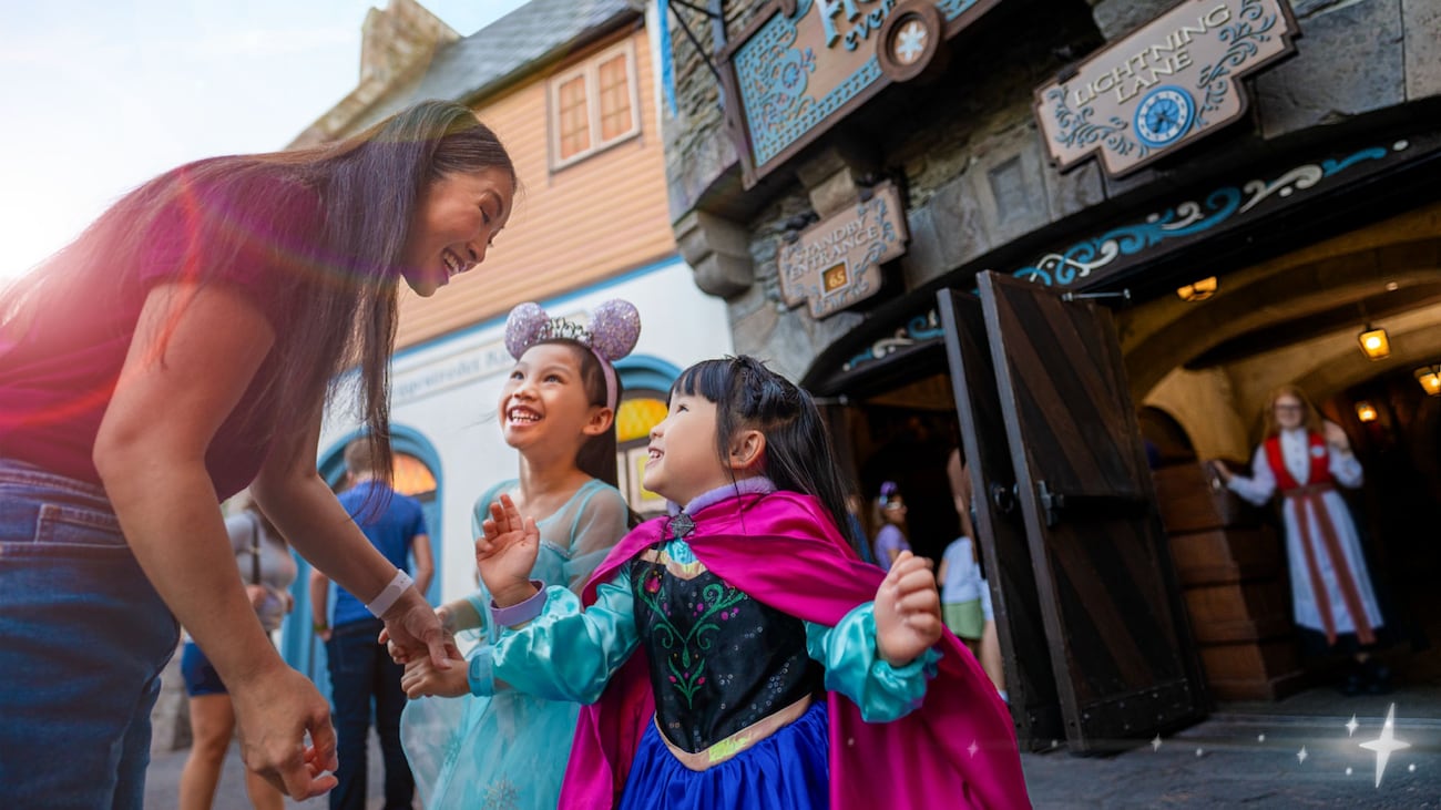 A mother and her 2 young daughters in Anna and Else outfits in front of Frozen Ever After