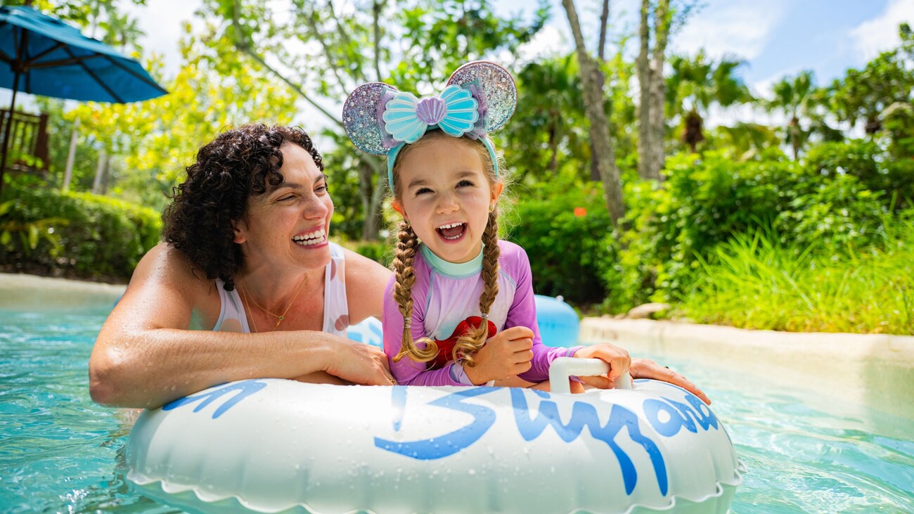 An adult holding onto an inner tube with a child sitting inside