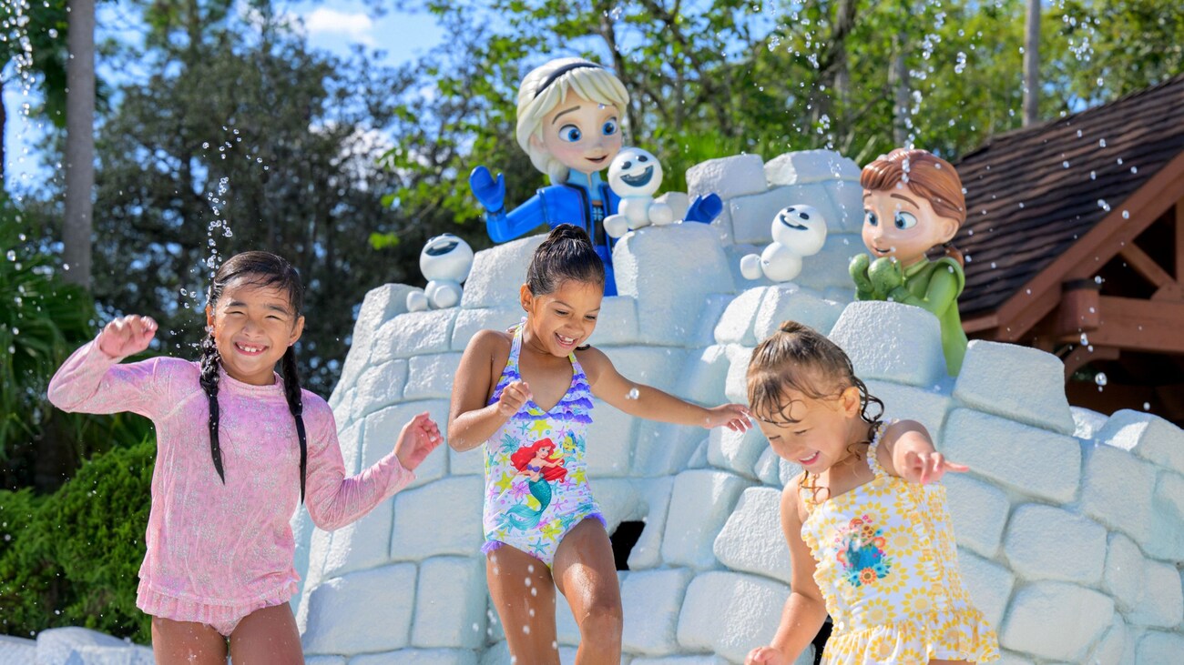 Tres chicas disfrutan un chapuzón cerca de una estatua de Anna y Elsa