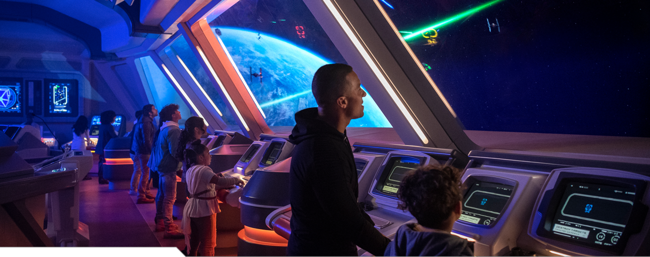 A crew member shows an excited young Guest a control panel aboard the Halcyon starcruiser