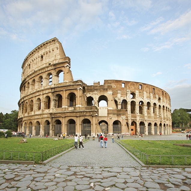 A stone pathway with people leads to the ruins of the Colosseum in Rome, Italy