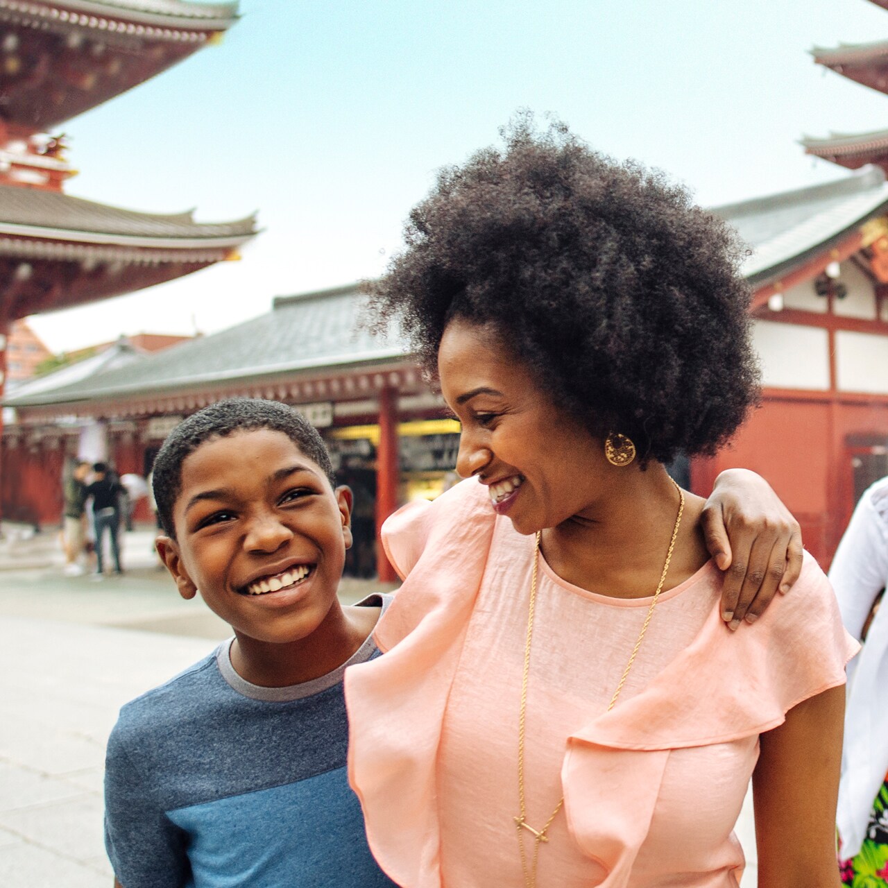 A family of 4 are all smiles as they walk in the courtyard of a Japanese temple