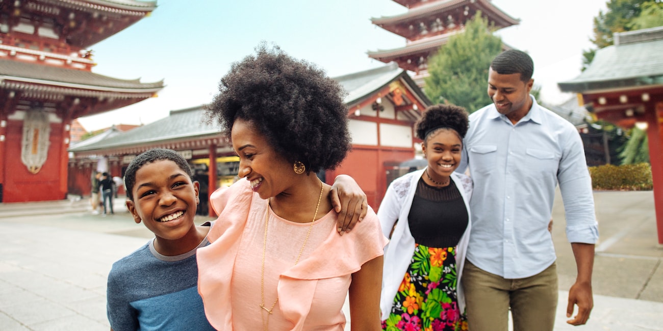 A family of 4 are all smiles as they walk in the courtyard of a Japanese temple