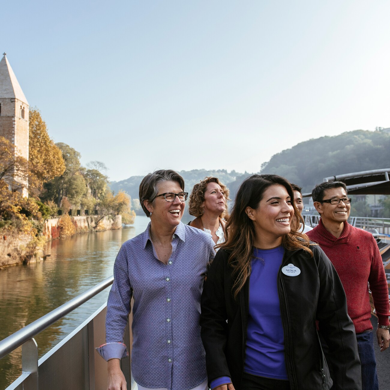 An Adventure Guide and 3 Adventurers pass a stone building and tower as they sail down the Rhône River