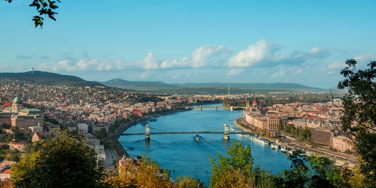 An Adventure Guide and 3 Adventurers pass a stone building and tower as they sail down the Rhône River
