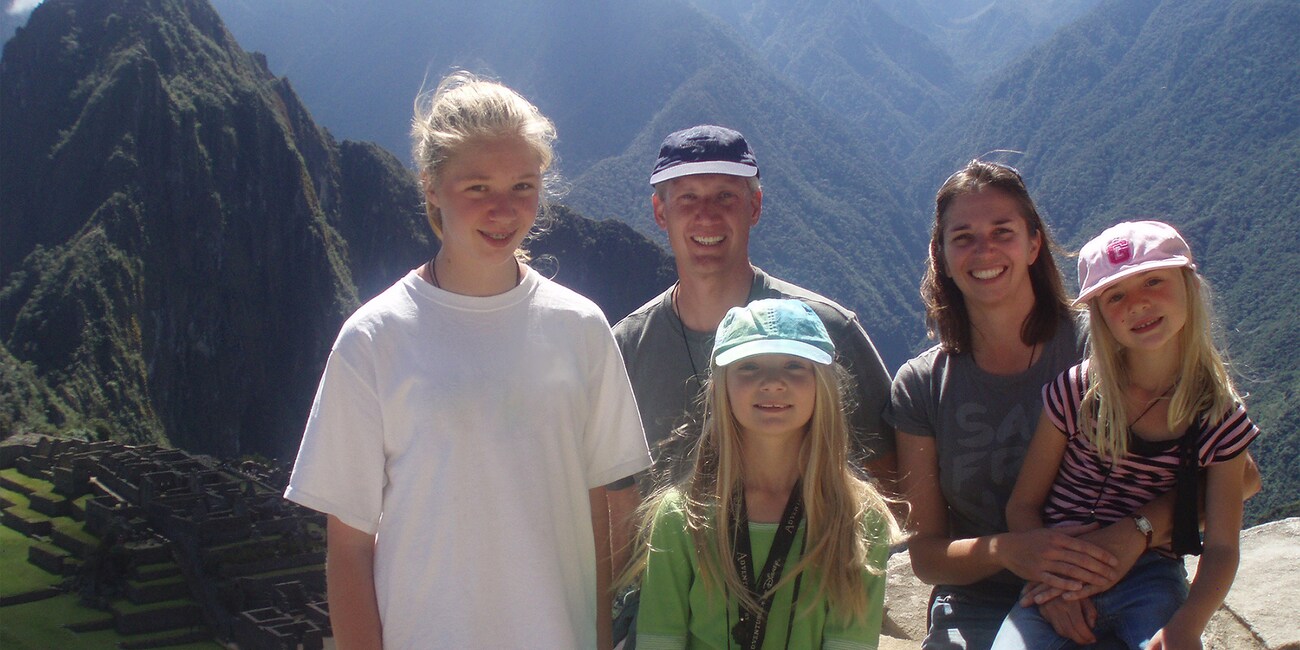 The Fimy family of five pose for a picture with the green mountains of Peru in the background