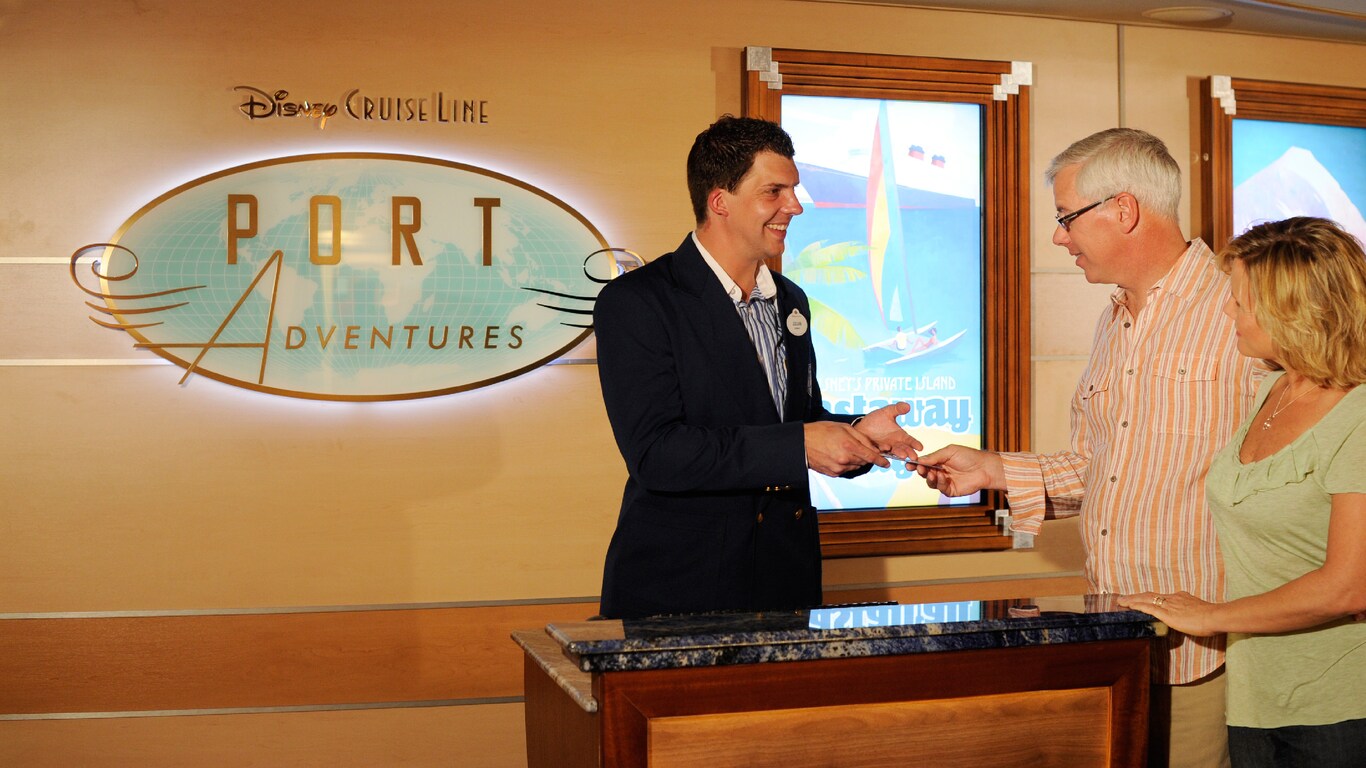 A Port Adventures representative assists a couple with their check in