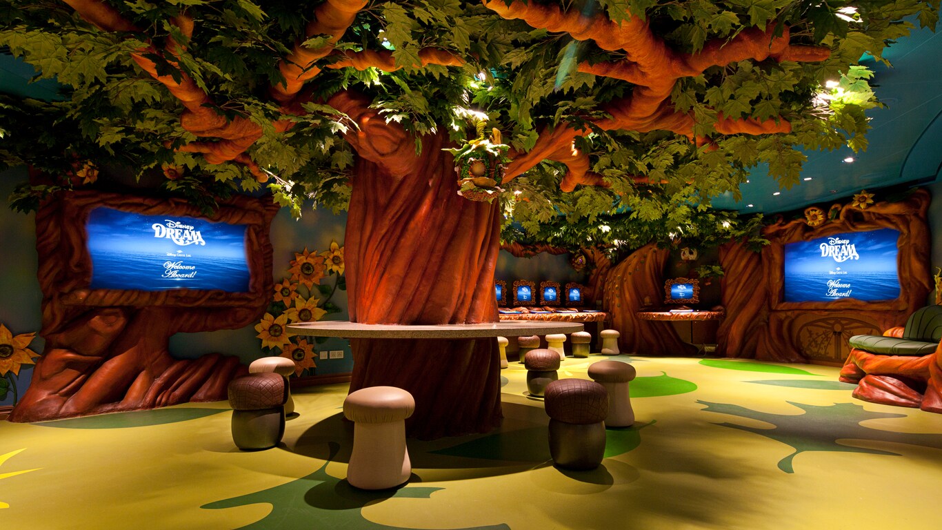 Seats shaped like mushrooms surround the trunk of a large tree in this fanciful youth club themed to resemble Pixie Hollow 